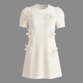White dress with floral embellishments on a gray background