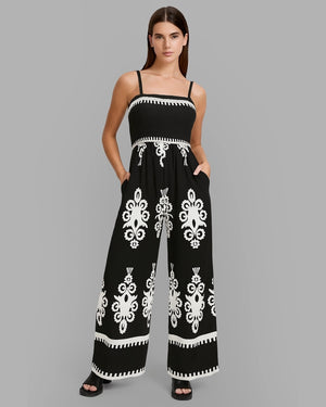 Woman wearing a black and white patterned jumpsuit on a gray background