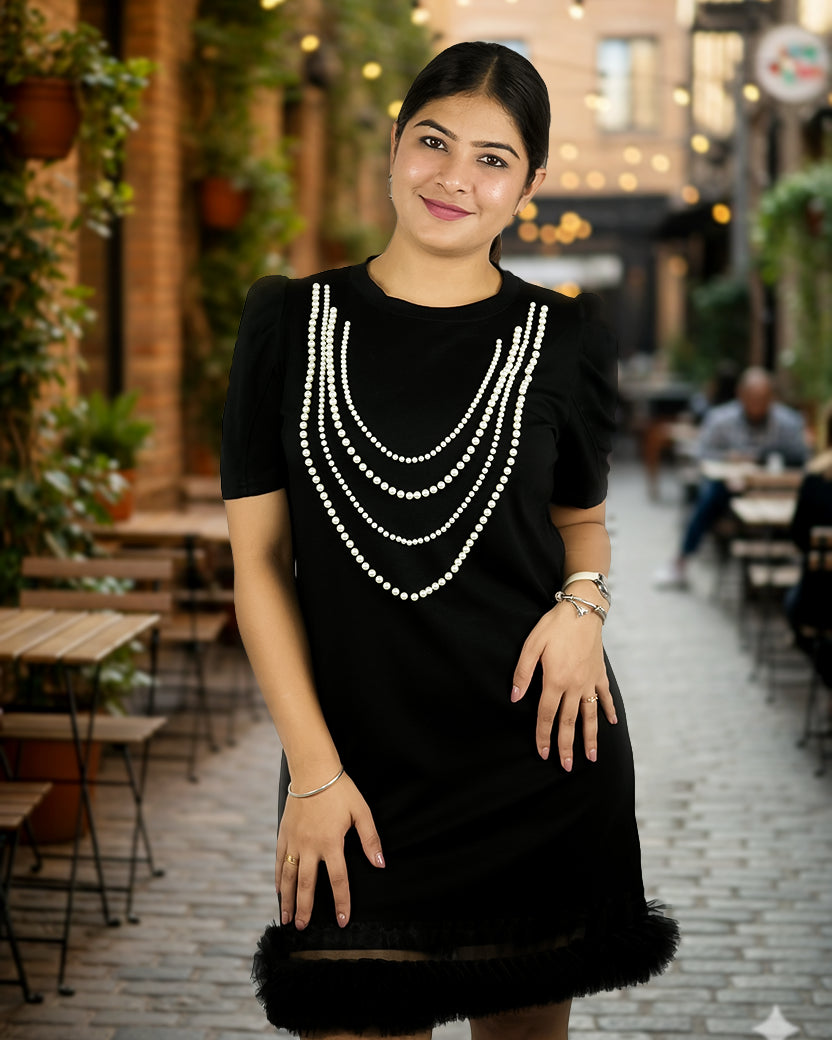 Woman wearing a black dress with white embellishments in an outdoor setting