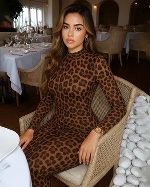 Woman in a leopard print dress sitting in a restaurant.