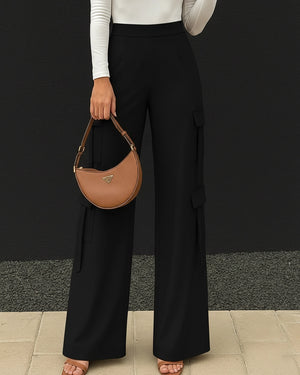 Person wearing black wide-leg pants and holding a brown handbag against a black background