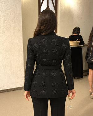 Woman wearing a black patterned blazer in an indoor setting
