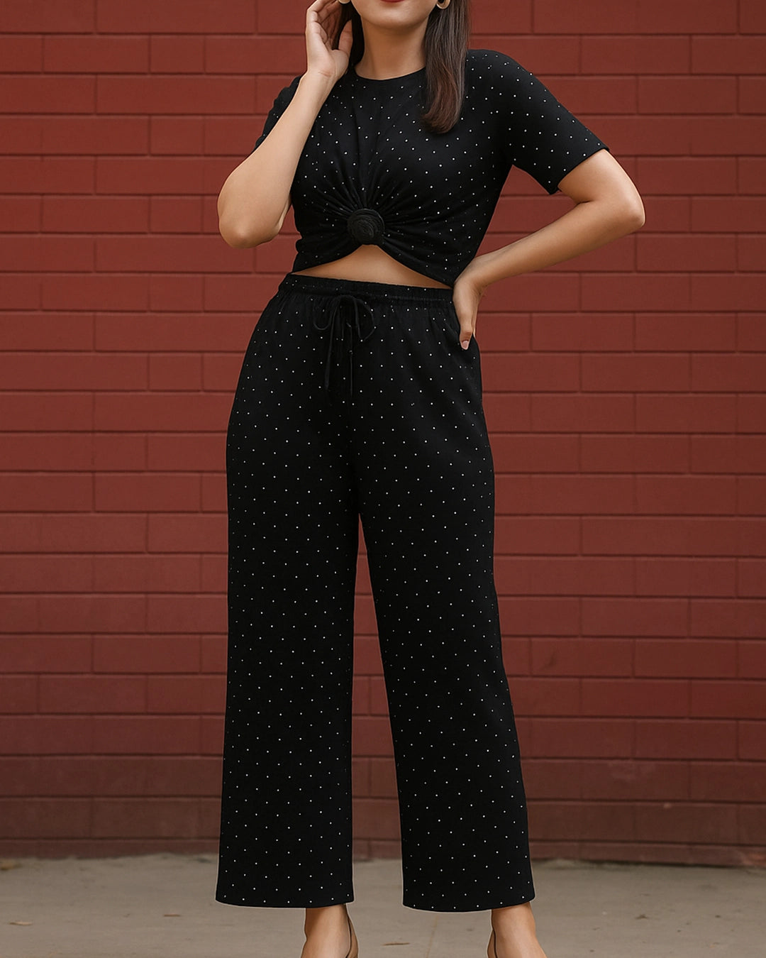 Person wearing a black polka dot outfit against a red brick wall