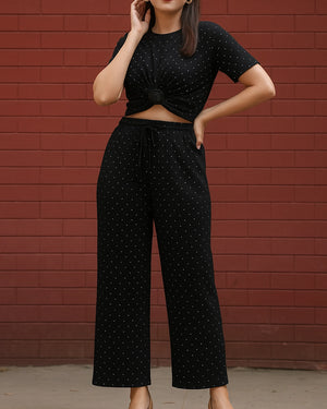 Person wearing a black polka dot outfit against a red brick wall
