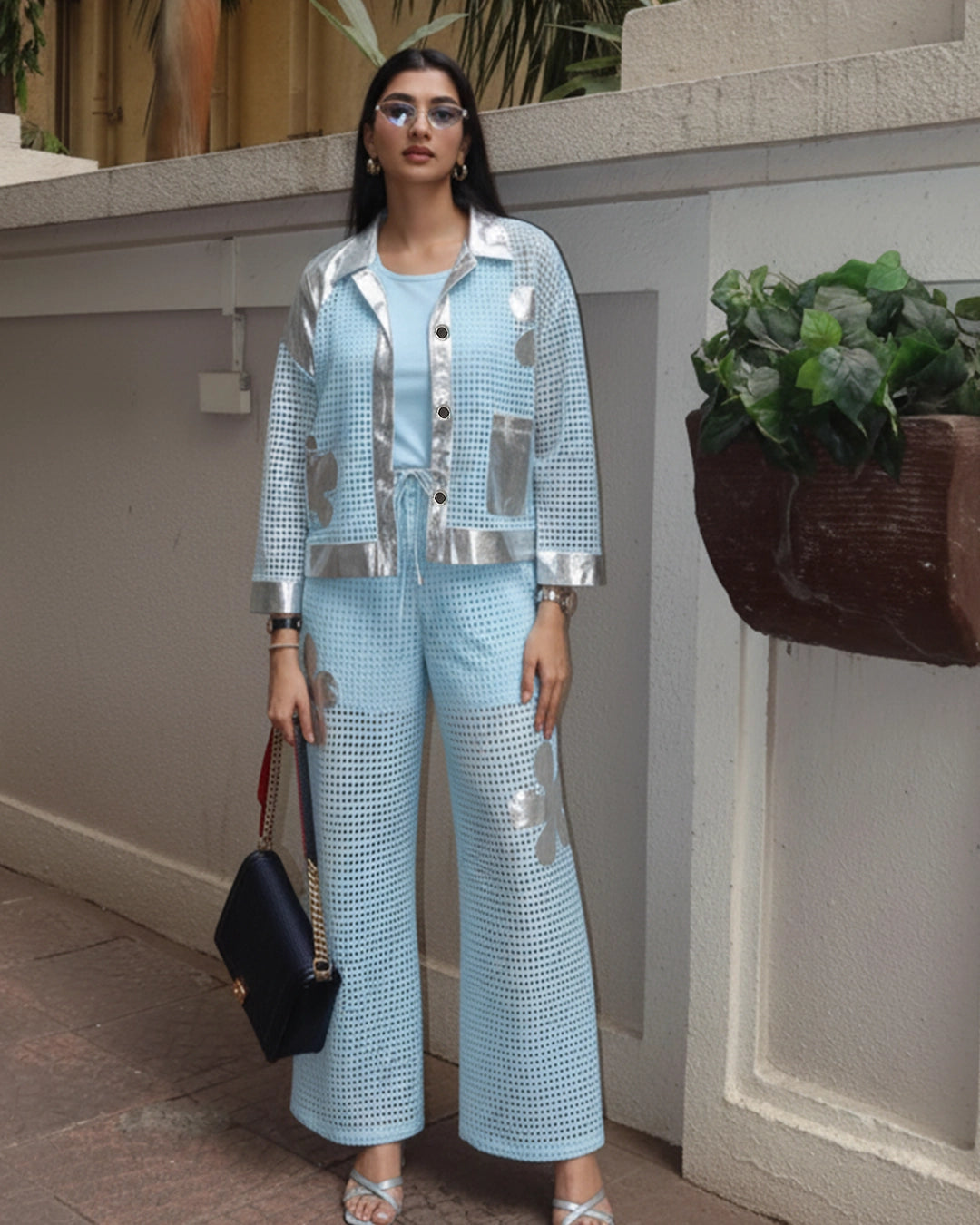 Woman in a light blue outfit with silver accents standing outdoors.
