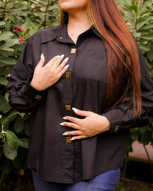 Person wearing a black button-up shirt with a blurred green background