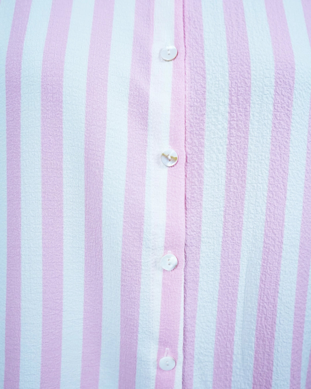 Close-up of a pink and white striped shirt with buttons.