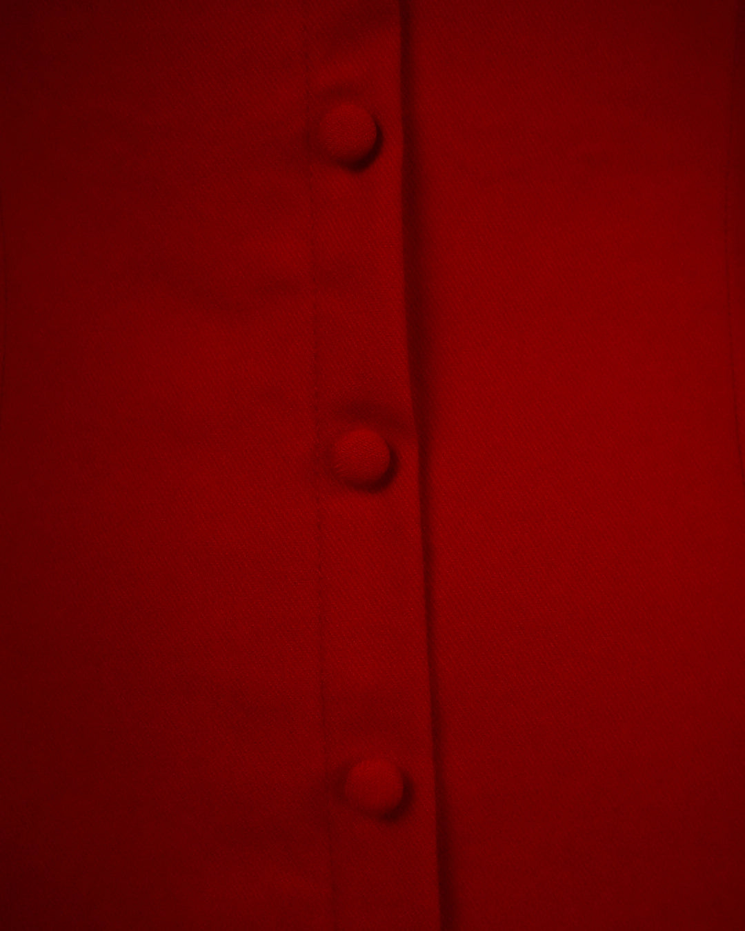 Close-up of a red fabric with buttons on a dark background