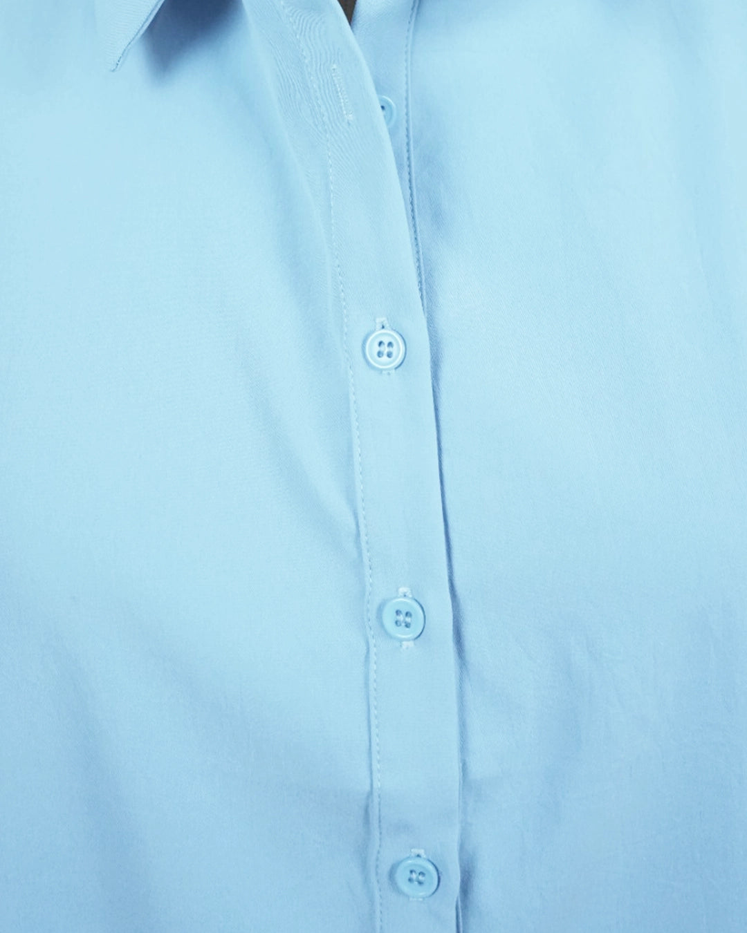 Close-up of a light blue shirt with buttons on a plain background