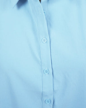 Close-up of a light blue shirt with buttons on a plain background