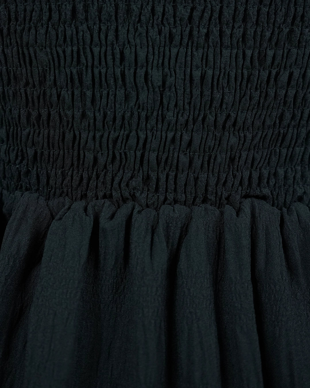 Close-up of dark green fabric with smocked waistband