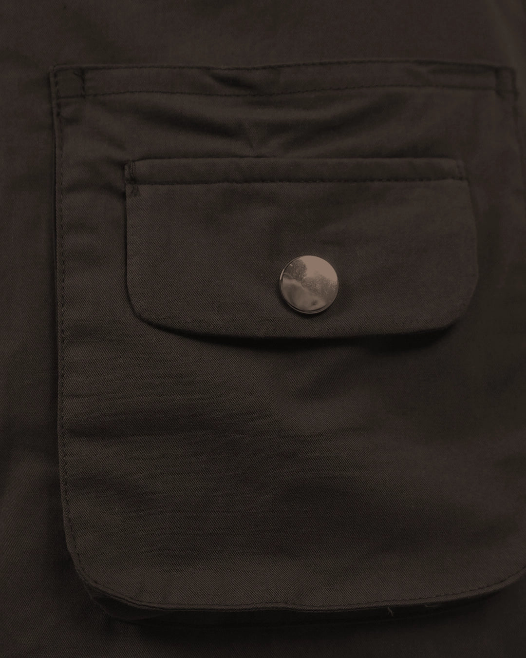Close-up of a dark brown jacket pocket with a button on a dark background