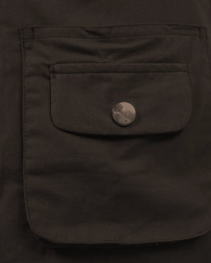Close-up of a dark brown jacket pocket with a button on a dark background
