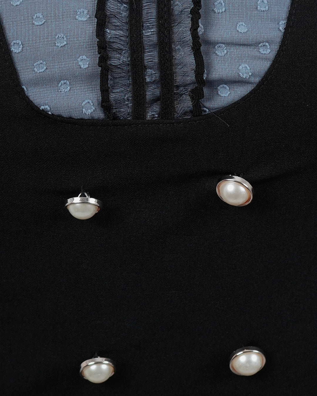 Close-up of a black coat with pearl buttons and a blue polka dot lining.