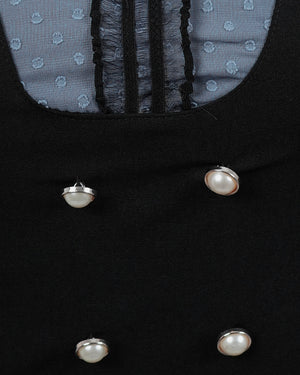 Close-up of a black coat with pearl buttons and a blue polka dot lining.