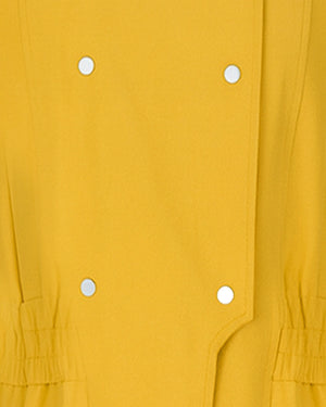 Close-up of a mustard yellow garment with white buttons.
