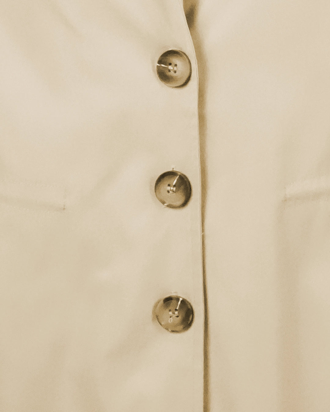 Close-up of a beige coat with gold buttons on a light background