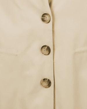 Close-up of a beige coat with gold buttons on a light background