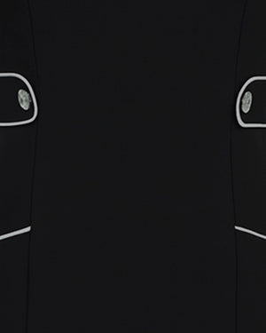 Close-up of a black coat with white buttons and trim on a dark background