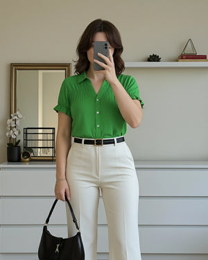 Person wearing a green shirt and white pants, taking a mirror selfie.