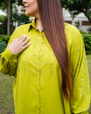Woman wearing a bright yellow shirt with decorative elements outdoors