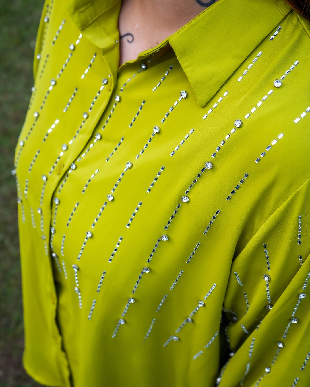 Close-up of a bright green shirt with silver embellishments on a blurred background