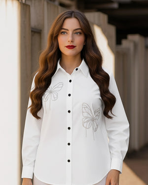 Woman wearing a white shirt with butterfly designs outdoors