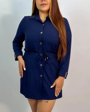 Woman wearing a navy blue dress with a belt against a plain background