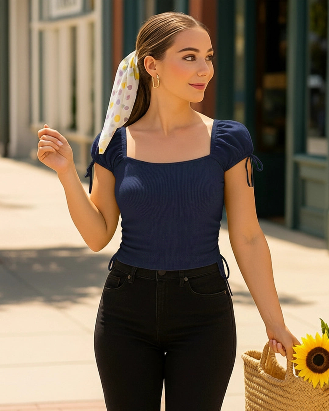 Woman wearing a navy blue top and black pants with a colorful headscarf, standing outdoors.