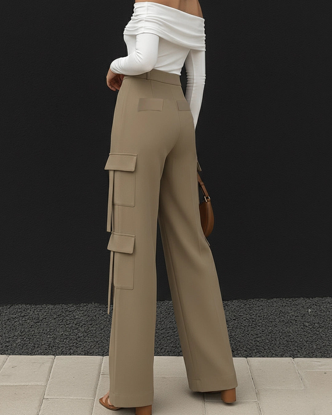 Person wearing beige cargo pants with a white top against a black background