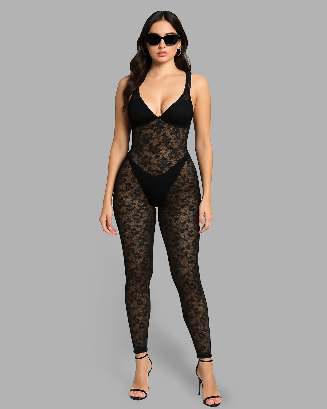 Woman wearing a black lace bodysuit on a gray background