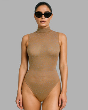 Woman wearing a beige bodysuit with subtle embellishments on a gray background