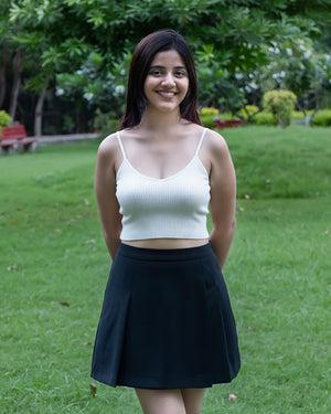 Woman wearing a white top and black skirt standing in a park.