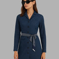 Woman wearing a navy blue dress with a belt on a gray background