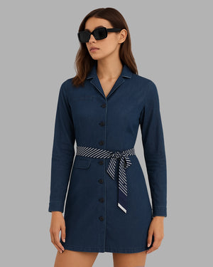 Woman wearing a navy blue dress with a belt on a gray background