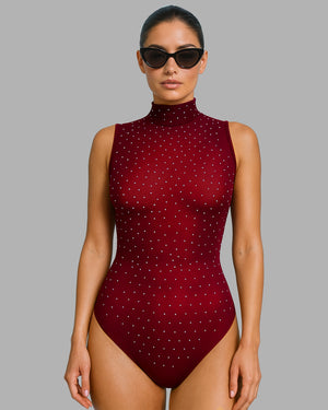 Woman wearing a maroon swimsuit with white polka dots on a gray background