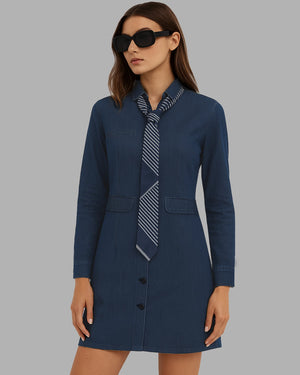 Woman wearing a navy blue dress with a patterned tie against a gray background