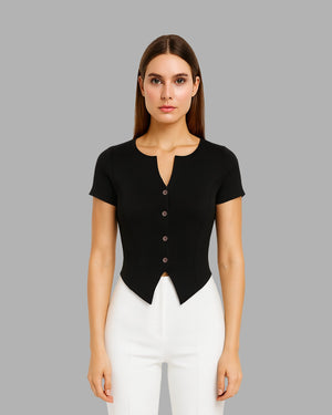 Woman wearing a black short-sleeve top with buttons and white pants on a gray background