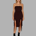 Woman wearing a strapless brown dress with a slit on a gray background