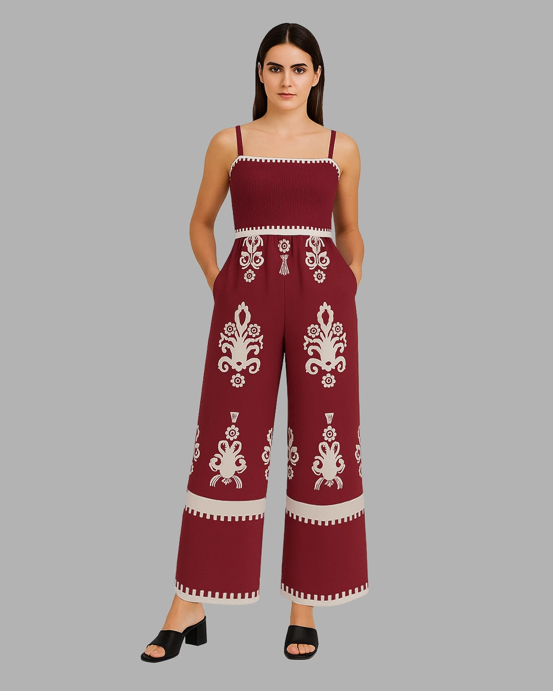 Woman wearing a maroon jumpsuit with white patterns on a gray background