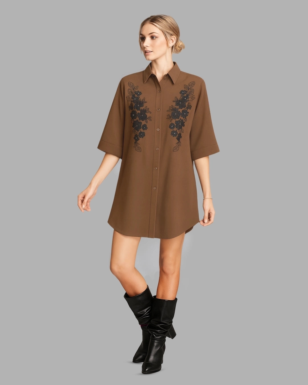 Woman wearing a brown dress with floral embroidery and black boots on a gray background
