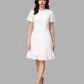 Woman wearing a white dress with ruffled hem on a gray background