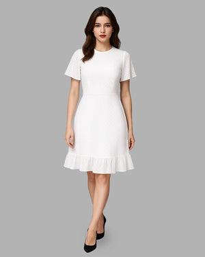 Woman wearing a white dress with ruffled hem on a gray background