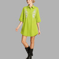Woman wearing a green dress with floral embroidery on a gray background