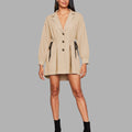 Woman wearing a beige trench coat on a gray background