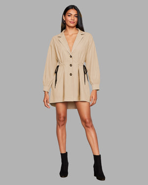 Woman wearing a beige trench coat on a gray background