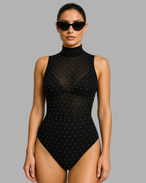 Woman wearing a black polka dot swimsuit against a gray background