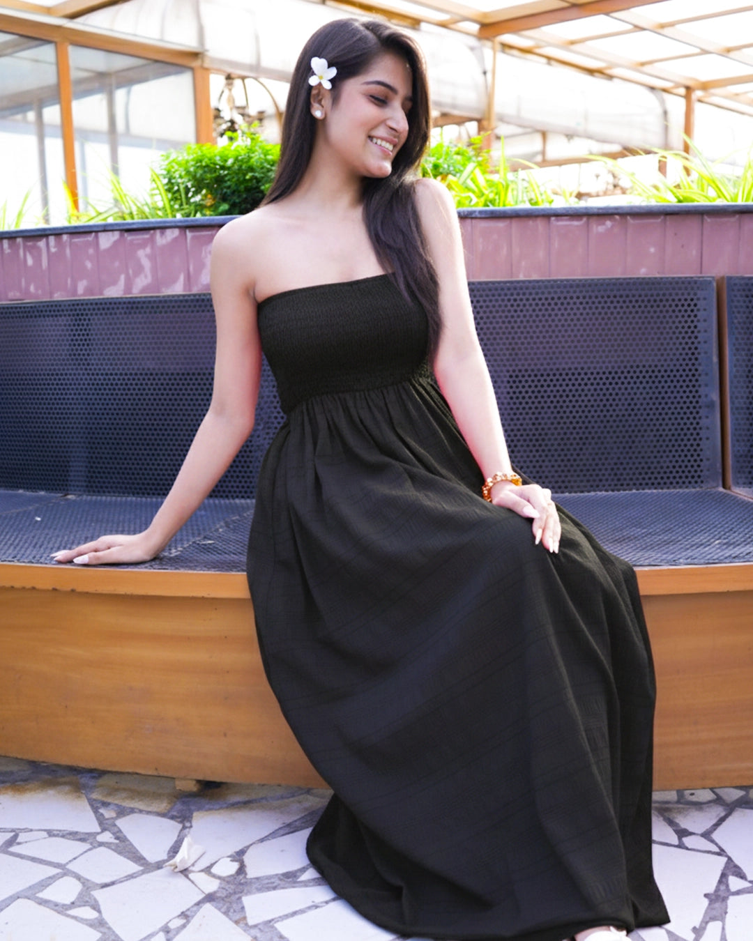 Woman in a black dress sitting on a bench outdoors