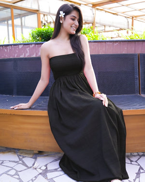 Woman in a black dress sitting on a bench outdoors