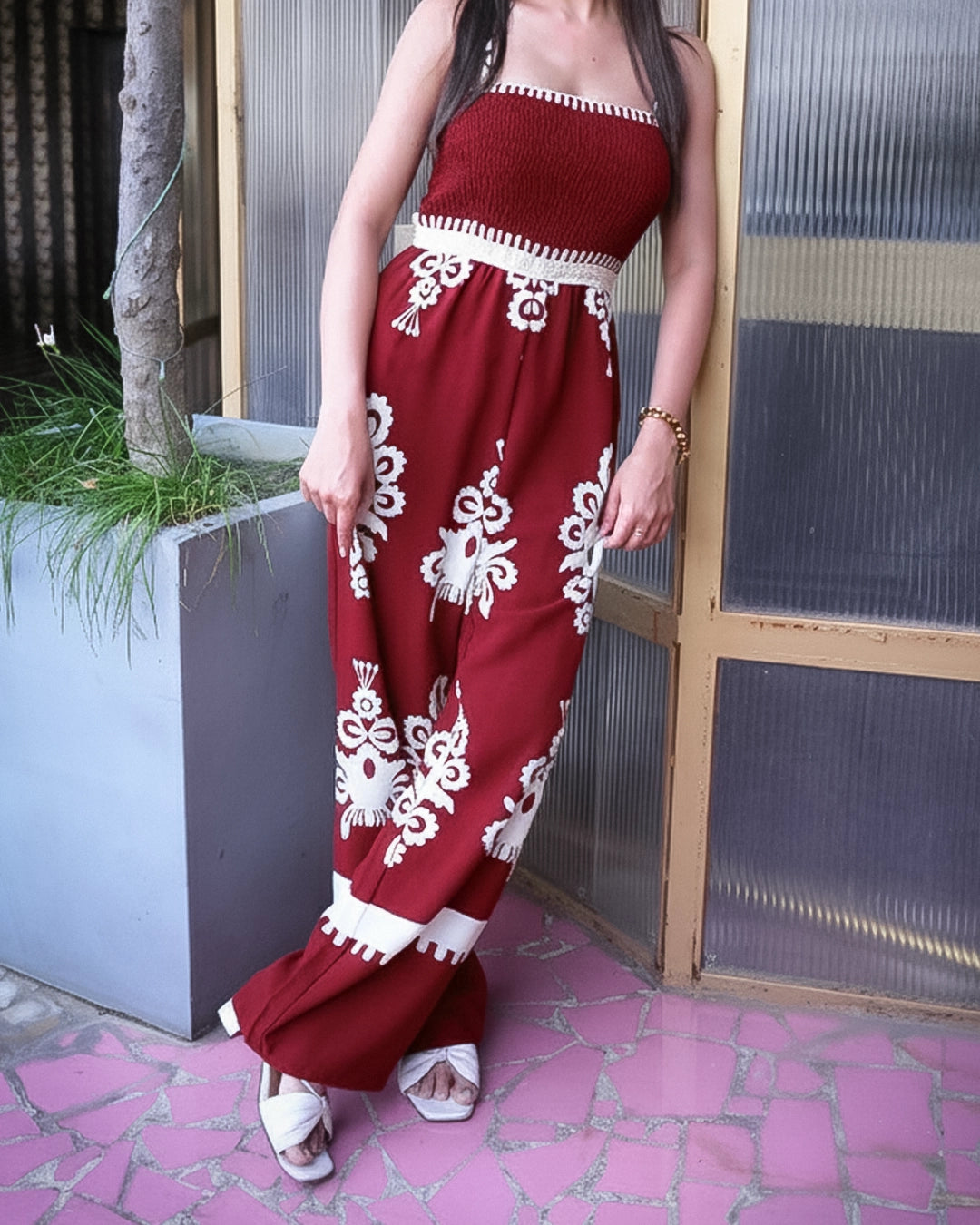 Person wearing a red and white floral dress standing outdoors.
